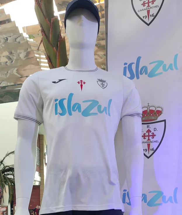 Primera equipación 2024/25 en un maniquí: camiseta blanca con ribetes negros, la cruz de Santiago y el escudo